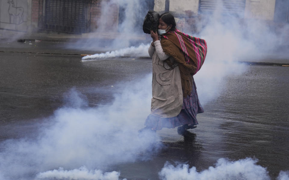 Una mujer corre a través de los gases lacrimógenos lanzados por la policía en el cuarto día de enfrentamientos cerca del mercado de coca en La Paz, Bolivia, el lunes 8 de agosto de 2022. (AP Foto/Juan Karita)