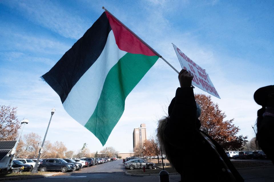 Nov 16, 2023; Columbus, Ohio, USA; A protestor holds a Palestinian flag on the front steps of The Ohio State University Longaberger Alumni House after they are made to leave the meeting. A demonstration was planned for protestors to speak during a meeting of the OSU Trustees calling for them to divest OSU funding from companies who have ties with Israeli fossil fuel companies operating in Palestine.