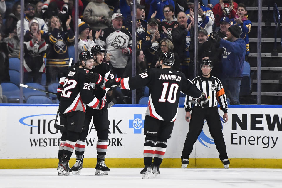 Buffalo Sabres center Dylan Cozens, center, celebrates with right wing Jack Quinn (22) and defenseman Henri Jokiharju (10) after scoring against the New Jersey Devils during the first period of an NHL hockey game in Buffalo, N.Y., Friday, March 24, 2023. (AP Photo/Adrian Kraus)