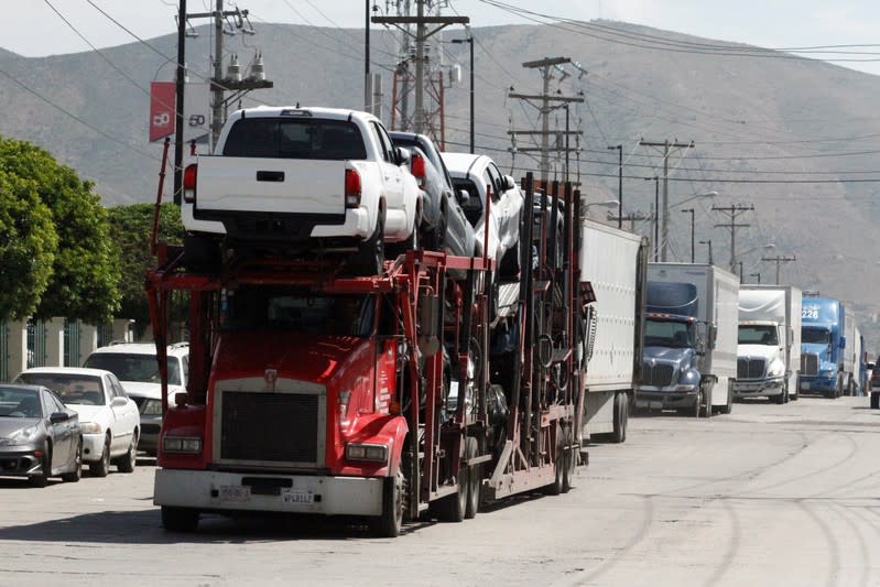 A car carrier transports Toyota trucks for delivery while waiting in queue for border customs control to cross into the U.S., at the Otay border crossing in Tijuana