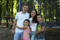 Volodymyr Zhdanov and his family pose in a park in Kyiv, Ukraine, Tuesday, Aug. 16, 2022. It was early one morning when life under Russian occupation became too much for Volodymyr Zhdanov: Rocket fire aimed at Ukrainian forces struck near his home in the city of Kherson, terrifying his young children. (AP Photo/Roman Hrytsyna)