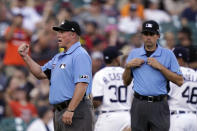 Umpire Marvin Hudson, left, makes the call after a review with umpire John Tumpane during the fifth inning of a baseball game between the Detroit Tigers and the Minnesota Twins, Saturday, July 23, 2022, in Detroit. A rule change at the beginning of the season designed to explain on-field call challenges and outcomes introduced umpires’ voices to ballpark speakers, to the fans in their seats and to the world at home for the first time. (AP Photo/Carlos Osorio)