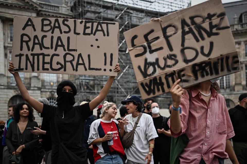 Protesters hold placards reading 