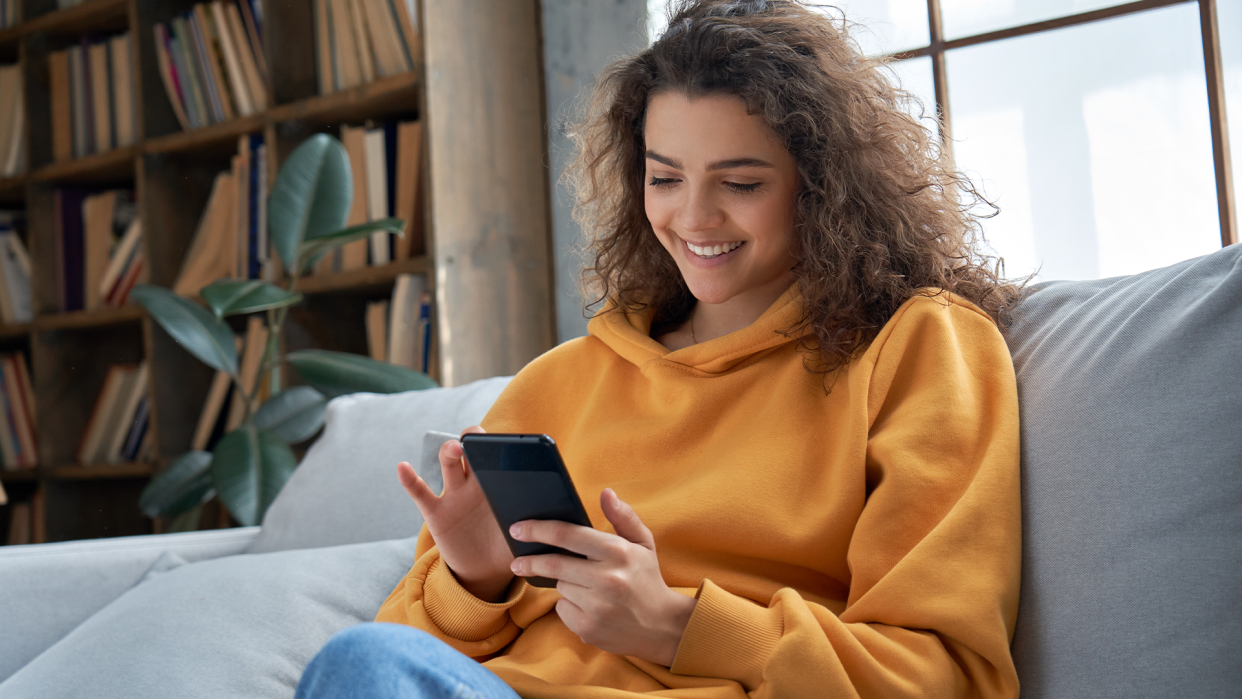  hispanic teen girl checking social media holding smartphone at home. 