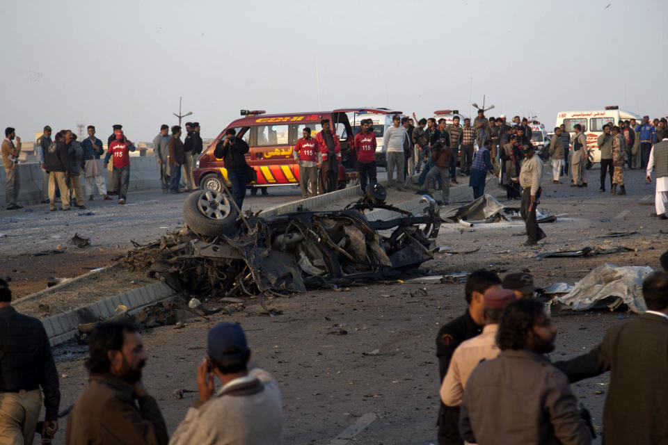 People gather at the site of bombing in Karachi, Pakistan, Thursday, Jan. 9, 2014. Police said a car bomb has killed a senior police investigator known for arresting dozens of Pakistani Taliban, as well as two other officers. (AP Photo/Shakil Adil)