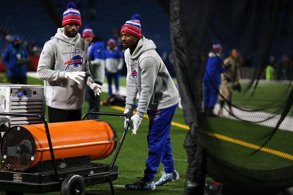 Bills players warm their hands in front of a heater on the sidelines prior to their wild-card game last week.