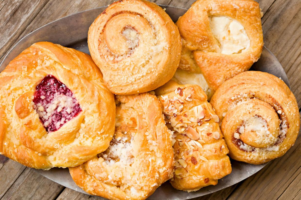 A high angle close up shot of a variety of danish pastry on an old pewter plater. Shot on a grungy old wooden table.