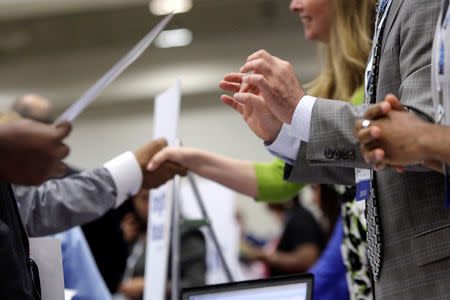 Corporate recruiters (R) gesture and shake hands as they talk with job seekers at a Hire Our Heroes job fair targeting unemployed military veterans and sponsored by the Cable Show, a cable television industry trade show in Washington, June 11, 2013. REUTERS/Jonathan Ernst/File Photo