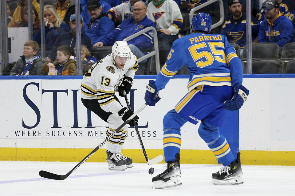 Boston Bruins' Charlie Coyle (13) controls the puck as St. Louis Blues' Colton Parayko (55) defends during the first period of an NHL hockey game Saturday, Jan. 13, 2023, in St. Louis. (AP Photo/Scott Kane)