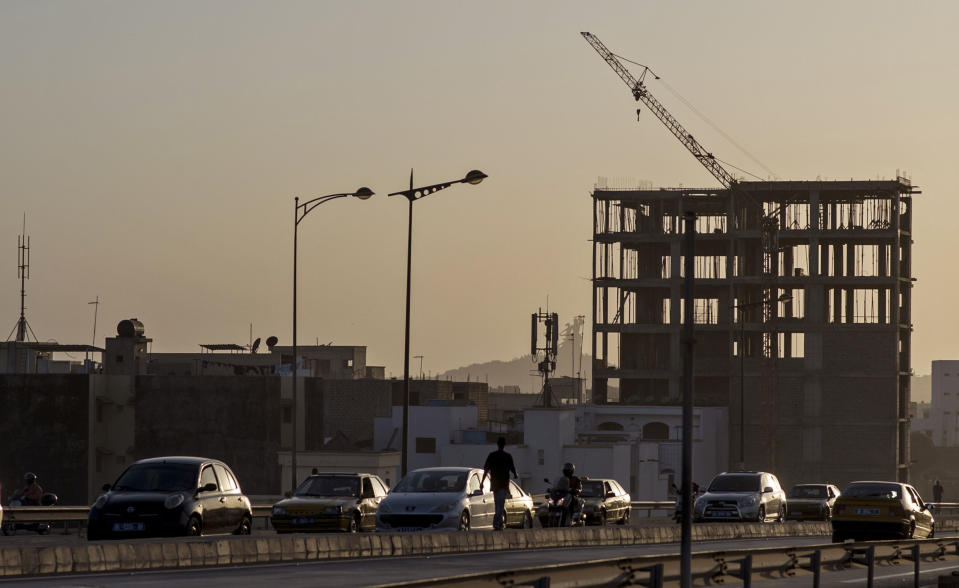 In this photo taken on Tuesday, Feb. 11, 2014, traffic passes a residential building under construction in Dakar, Senegal. President Macky Sall successfully ran on a campaign to lower living costs and now a new law mandates across-the-board rent reductions in Senegal, although everybody knows enforcement will be tricky and some landlords will defy the threat of prison sentences as they fail to comply with the reductions after decades of increases.(AP Photo/Sylvain Cherkaoui)