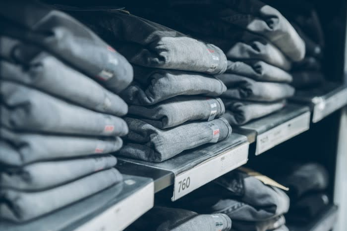 Faded denim blue jeans of different sizes on a store shelf.