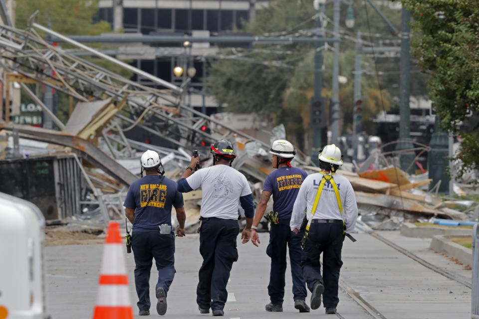 New Orleans Fire Department personnel walk toward the scene of the Hard Rock Hotel in New Orleans, Wednesday, Oct. 16, 2019. New Orleans officials say the chances of a missing worker's survival after the collapse are diminishing, and they have shifted their efforts from rescue to recovery mode. News outlets report Fire Department Superintendent Tim McConnell says they shifted Wednesday ahead of a possible tropical storm. McConnell says chances of the missing worker's survival will be considered nearly "zero" if no sign of him turns up by Wednesday night. (AP Photo/Gerald Herbert)