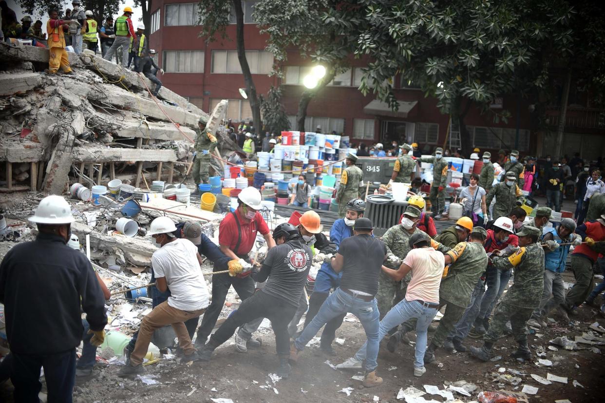 Rescuers, firefighters, policemen, soldiers and volunteers search for survivors in a flattened building in Mexico City: Getty