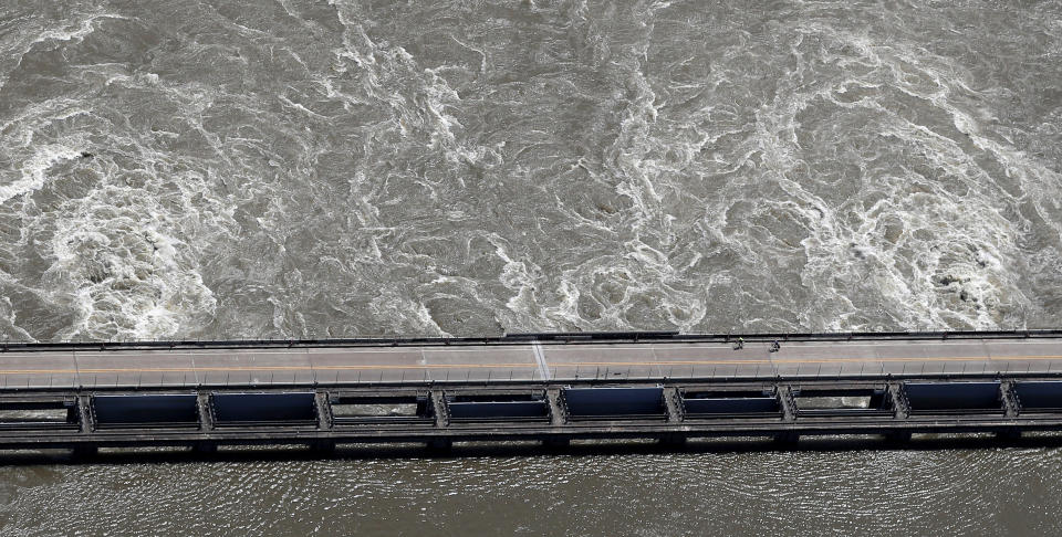 In this Wednesday, May 29, 2019 photo, two cyclists ride along the Old River Control Structure, as swelling waters from the Mississippi River are diverted through the U.S. Army Corps of Engineers structure into the Atchafalaya Basin, in Vidalia, La. (AP Photo/Gerald Herbert)