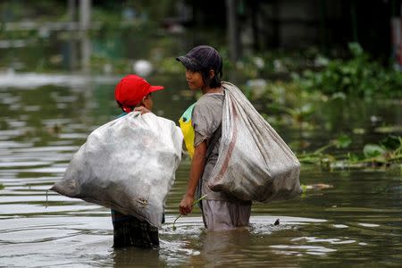 Children walk through flooded road as they collect water bottles in Kyaung Kone in Ayeyarwady division, Myanmar, August 12, 2016. REUTERS/Soe Zeya Tun