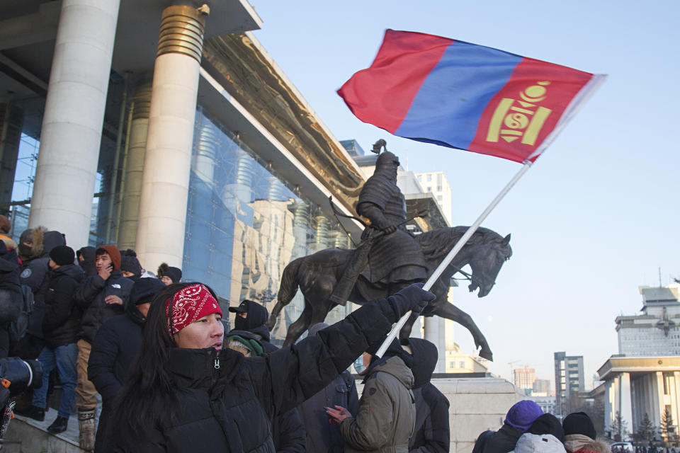 A protester waves a Mongolian national flag as protesters gather on the steps of the State Palace in Ulaanbaatar in Mongolia on Monday, Dec. 5, 2022. Protesters angered by allegations of corruption linked to Mongolia's coal trade with China have stormed the State Palace in the capital, demanding dismissals of officials involved in the scandal. (AP Photo/Alexander Nikolskiy)