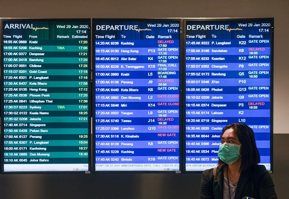 A woman wearing face mask stands in front of the flight information screen at KLIA2 in Sepang January 29, 2020. — AFP pic