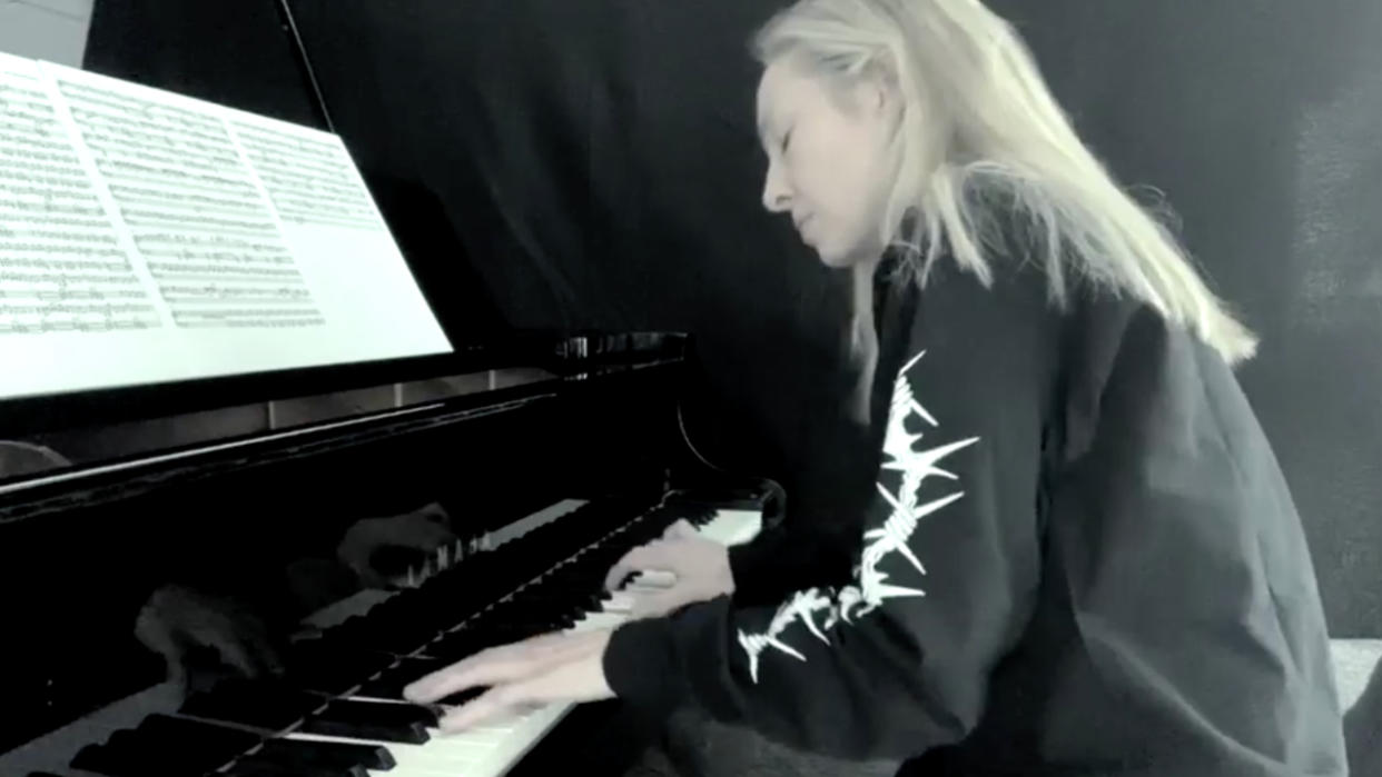  A blonde woman in a black, long-sleeve shirt playing piano. 