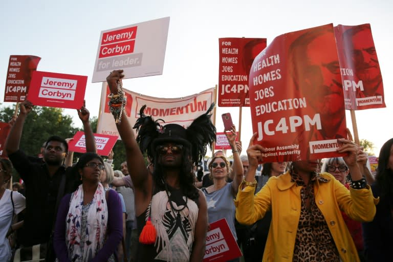 Supporters of Jeremy Corbyn hold up placards showing the Momentum logo as they cheer at a Black, Asian and minority ethnic (BAME) rally in north London