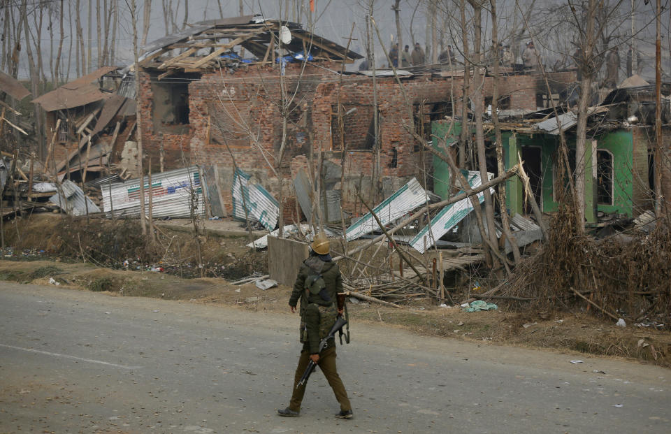 Indian policemen walk past the residential houses damaged in a gun-battle in Mujagund area some 25 Kilometers (16 miles) from Srinagar, Indian controlled Kashmir, Sunday, Dec. 9, 2018. Indian troops killed three suspected rebels in the outskirts of disputed Kashmir's main city ending nearly 18-hour-long gunbattle, officials said Sunday. (AP Photo/Mukhtar Khan)
