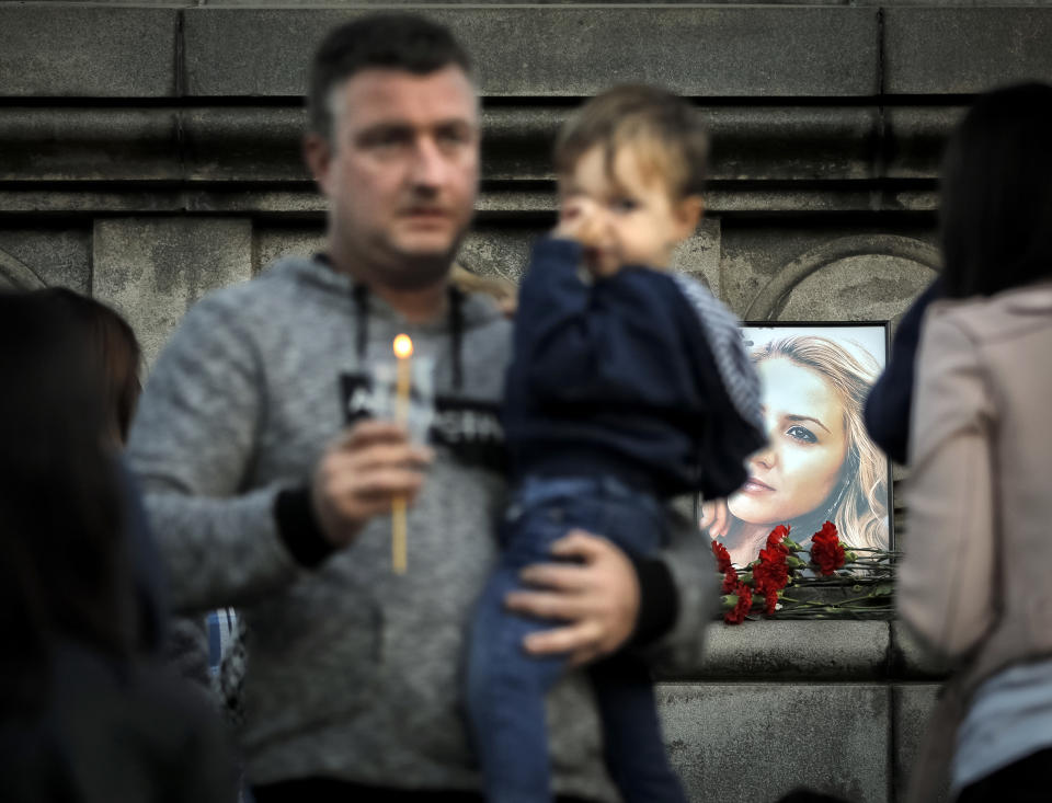 A portrait of slain television reporter Viktoria Marinova is placed on the Liberty Monument as people wait to place flowers and candles during a vigil in Ruse, Bulgaria, Monday, Oct. 8, 2018. Bulgarian police are investigating the rape, beating and slaying of a female television reporter whose body was dumped near the Danube River after she reported on the possible misuse of European Union funds in Bulgaria. Authorities discovered the body of 30-year-old Viktoria Marinova on Saturday in the northern town of Ruse near the Romanian border. One Bulgarian media site demanded an EU investigation, fearing that Bulgarian officials were complicit in the corruption.(AP Photo/Vadim Ghirda)