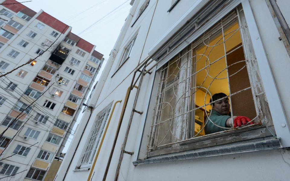 A woman removes broken glass from an apartment block