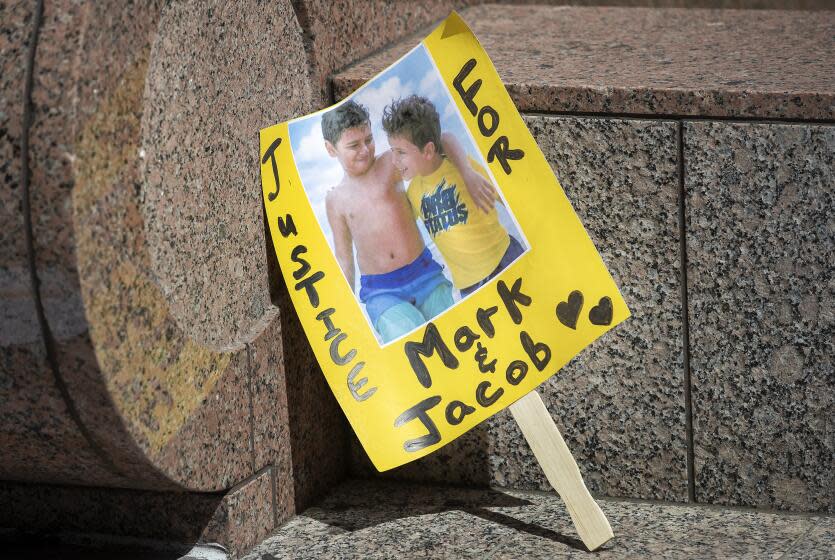 VAN NUYS, CA-APRIL 25, 2022: A sign shows an image of Mark Iskander, 11, left, and his brother Jacob Iskander, 8, outside of Van Nuys Courthouse were a preliminary hearing was held for Rebecca Grossman who is charged with murder and other counts stemming from a crash in Westlake Village, where Grossman's Mercedes struck the boys in a crosswalk and killed them. (Mel Melcon / Los Angeles Times)