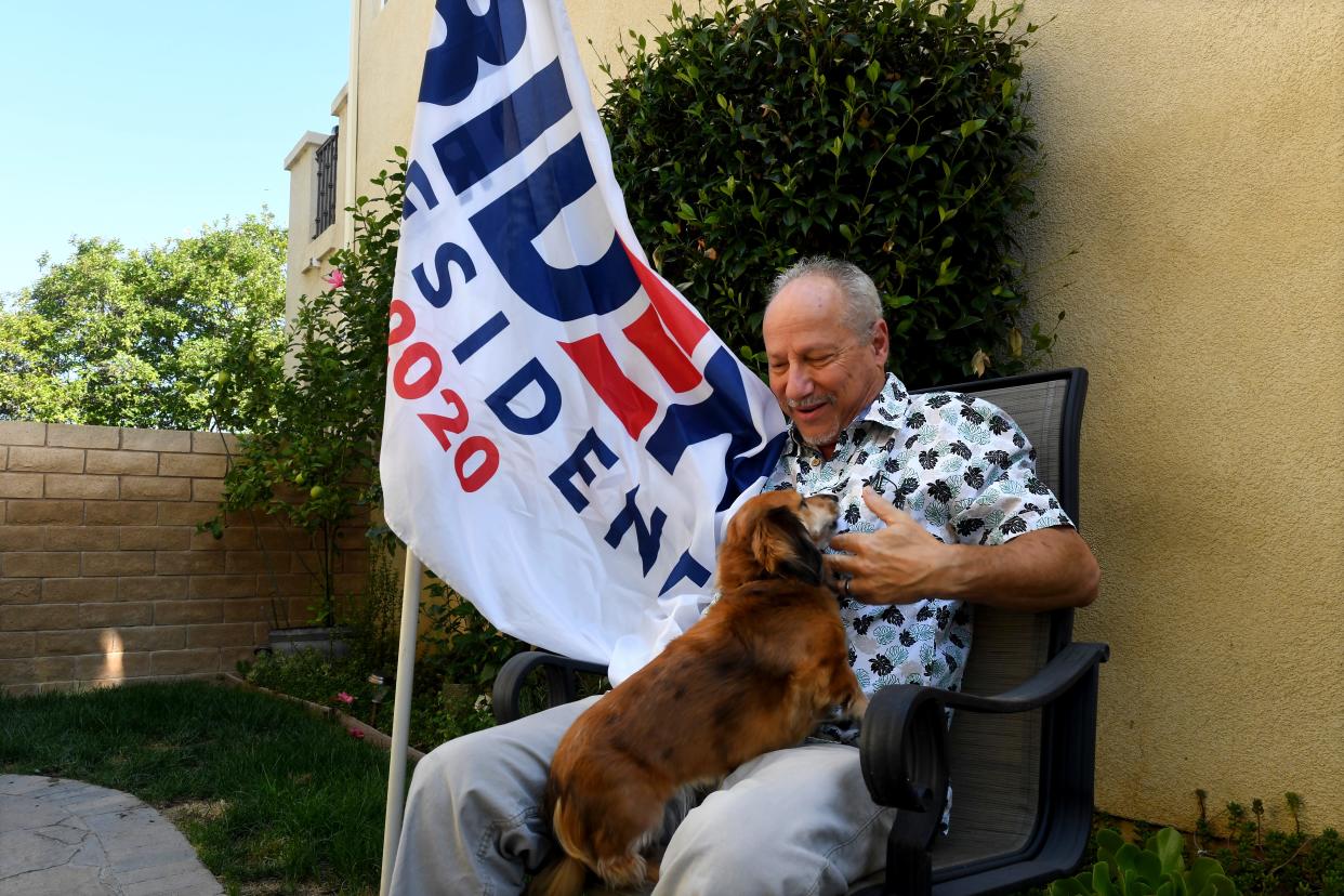 John Lapper of Simi Valley is joined by his dog, Pickles, as he displays the flag he'll take to a protest at Wednesday's presidential primary debate at the Ronald Reagan Presidential Library & Museum in Simi Valley.
