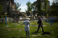 Local residents stand next to a school destroyed in a Russian bombing in Bakhmut, eastern Ukraine, Tuesday, May 24, 2022. The town of Bakhmut has been coming under increasing artillery strikes, particularly over the last week, as Russian forces try to press forward to encircle the city of Sieverodonetsk to the northeast. (AP Photo/Francisco Seco)