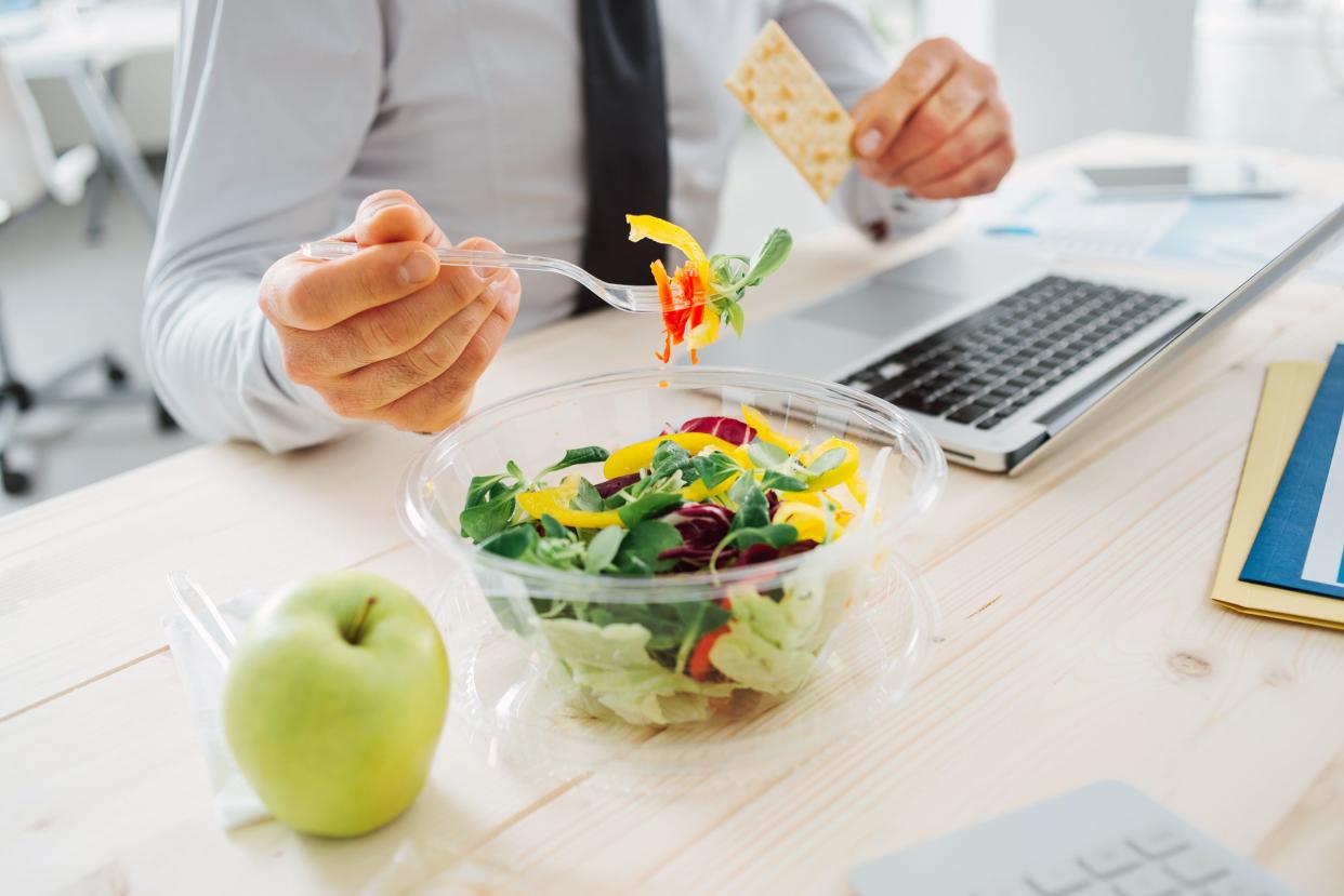 business man eating salad at desk