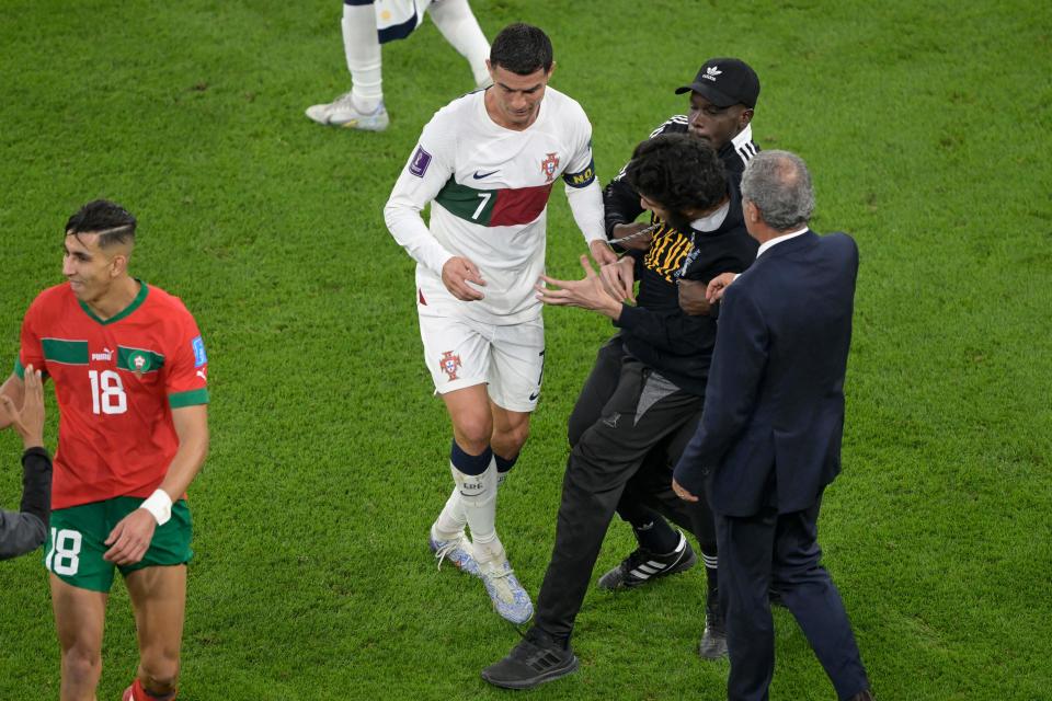 A pitch invader is caught next to Portugal's forward #07 Cristiano Ronaldo as he leaves the field after losing to Morocco 1-0 in the Qatar 2022 World Cup quarter-final football match between Morocco and Portugal at the Al-Thumama Stadium in Doha on December 10, 2022. (Photo by JUAN MABROMATA / AFP) (Photo by JUAN MABROMATA/AFP via Getty Images)