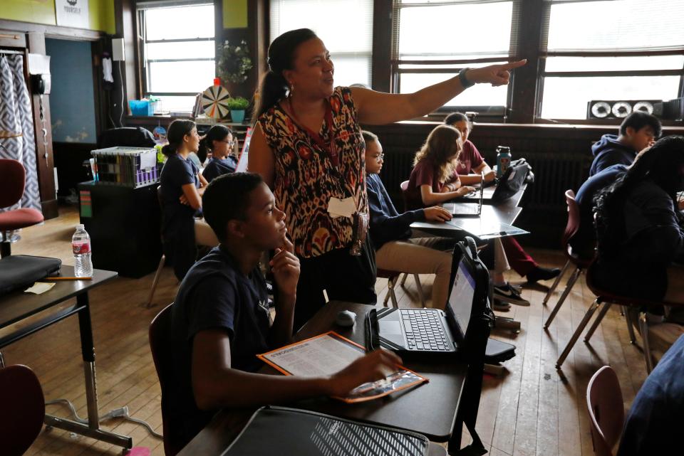 Technology Specialist Darlese Monteiro works with students at the Global Learning Charter Public School in New Bedford which is celebrating its 20th anniversary.