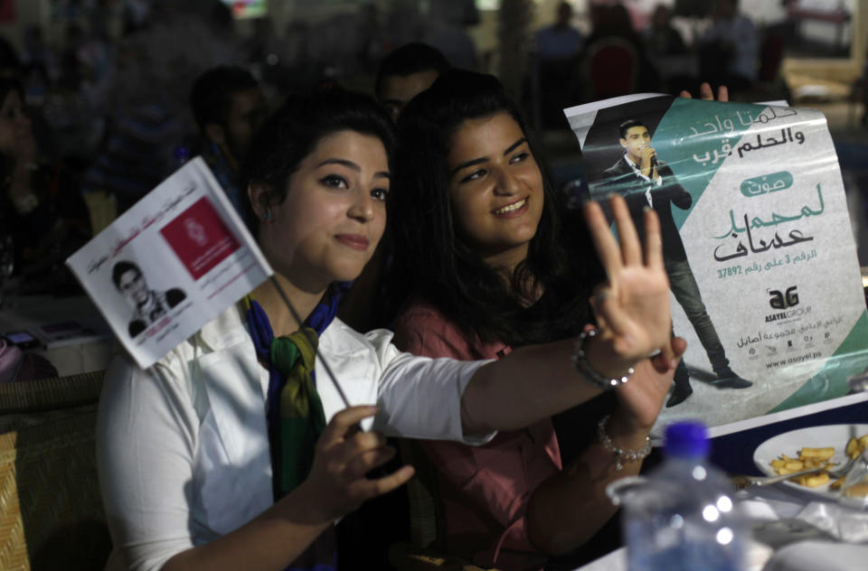 Palestinians hold pictures of Palestinian singer Mohammed Assaf while watching the contestant perform in a regional TV singing contest, in Gaza City, Saturday, June 22, 2013. Palestinians relished a rare moment of pride and national unity Saturday after the 23-year-old wedding singer from a refugee camp in the Gaza Strip won “Arab Idol,” a regional TV singing contest watched by millions of people. (AP Photo/Hatem Moussa)