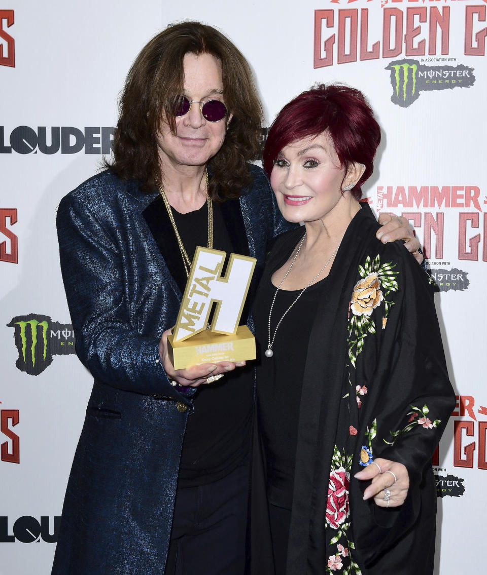 Rock frontman Ozzy Osbourne holds his Golden God award, standing with his wife Sharon Osbourne in the press room during the Metal Hammer Golden Gods Awards 2018 ceremony in London, Monday June 11, 2018. (Ian West/PA via AP)