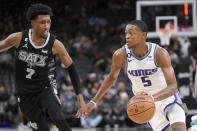 Sacramento Kings' De'Aaron Fox (5) drives against San Antonio Spurs' Josh Richardson (7) during the first half of an NBA basketball game, Sunday, Jan. 15, 2023, in San Antonio. (AP Photo/Darren Abate)