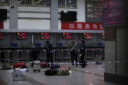 Police stand near luggage left at the ticket office after a group of armed men attacked people at Kunming railway station, Yunnan province, in this March 2, 2014 file photo. REUTERS/Stringer/Files