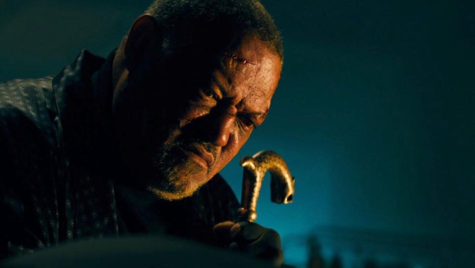 Laurence Fishburne's scarred Bowery King holds his cane while talking to John Iwck in Chapter 3