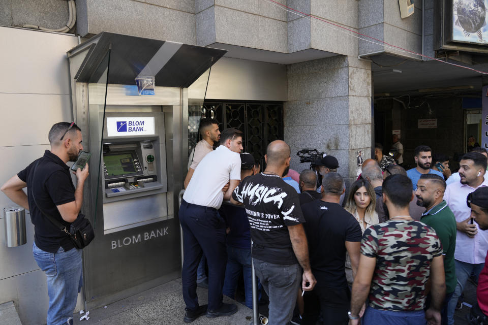 Media and security gather outside BLOM bank branch where a man who is identified as Abed Soubra is allegedly holding hostages in an effort to get to funds in his account in Beirut, Lebanon, Friday, Sept. 16, 2022. Depositors broke into at least four banks in different parts of crisis-hit Lebanon Friday demanding that they get their trapped savings as chaos spreads in the small Mediterranean nation in the middle of a historic economic meltdown. (AP Photo/Bilal Hussein)