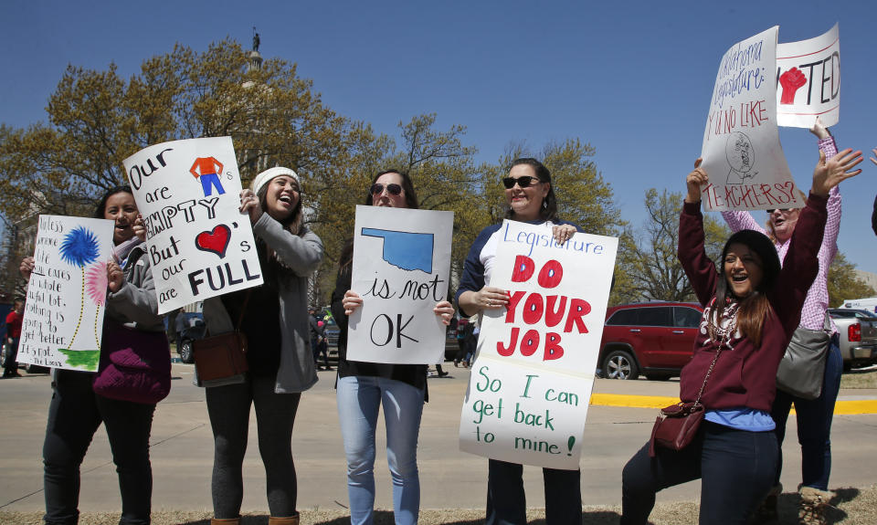 Elementary school teachers in the Putnam City school district of Oklahoma City wave signs at passing cars this week outside the state capitol. (AP) 