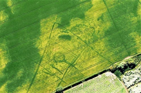 <span class="caption">Unseen from ground level, this Iron Age farmstead with recognisable round house near the Yorkshire Wolds is revealed in cropmarks. The lighter green shows it was carefully placed on a gravel rise surrounded by wetter land, shown here where the crop grows a darker green.</span> <span class="attribution"><span class="source">Peter Halkon</span>, <span class="license">Author provided</span></span>