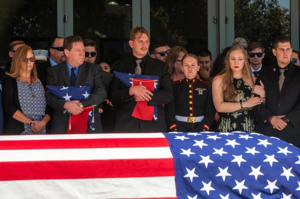 After the service for fallen marine Sgt. Nicole Gee, her father Richard Herrera, left, and husband Jarod Gee hold flags at Bayside Church’s Adventure Campus in Roseville on Saturday Sept. 18, 2021, as her casket is moved to the hearse. Sgt. Gee lost her life, along with 12 other U.S. service members, in the bombing attack at the Kabul airport on Aug. 26. RenÈe C. Byer/rbyer@sacbee.com