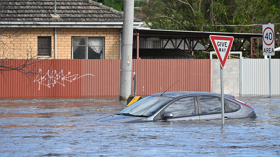 A car submerged in flood waters at Maribyrnong, in front of a house.