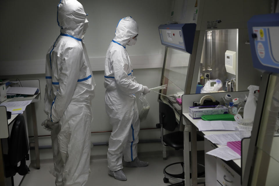 French lab scientists in hazmat gear inserting liquid in test tube manipulate potentially infected patient samples at Pasteur Institute in Paris, Thursday, Feb. 6, 2020. Scientists at the Pasteur Institute developed and shared a quick test for the new virus that is spreading worldwide, and are using genetic information about the coronavirus to develop a potential vaccine and treatments. (AP Photo/Francois Mori)