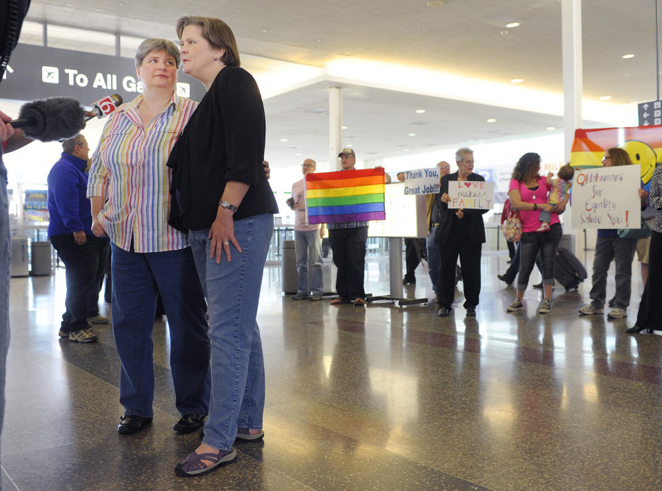 Sharon Baldwin, left, and her partner Mary Bishop speak with members of the media before boarding a plane to Denver at Tulsa International Airport, Wednesday, April 16, 2014. Oklahomans for Equality gathered at Tulsa International Airport with their signs for a send off celebration in support for the plaintiffs, including Baldwin and Bishop, in the Oklahoma Marriage Equality lawsuit as they head to the 10th Circuit Court of Appeals in Denver. (AP Photo/Brandi Simons)