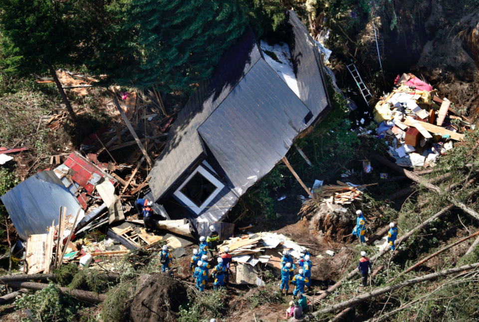 <em>Police search missing persons around houses destroyed by a landslide (AP)</em>