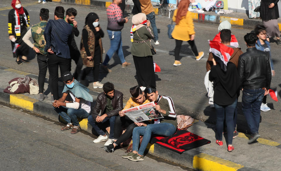 Protesters share a copy of the "Tuk-Tuk" newspaper, in Tahrir Square, Baghdad, Iraq, Wednesday, Nov. 20, 2019. A small group of Iraqi volunteers is working in secrecy to produce the newspaper that aims to be the voice of the largest grassroots protest movement in the country’s modern history. Its editors say the newspaper is vital amid shutdowns of the internet, filling a void left by mainstream Iraqi journalists who either back the government or fear retaliation. (AP Photo/Hadi Mizban)