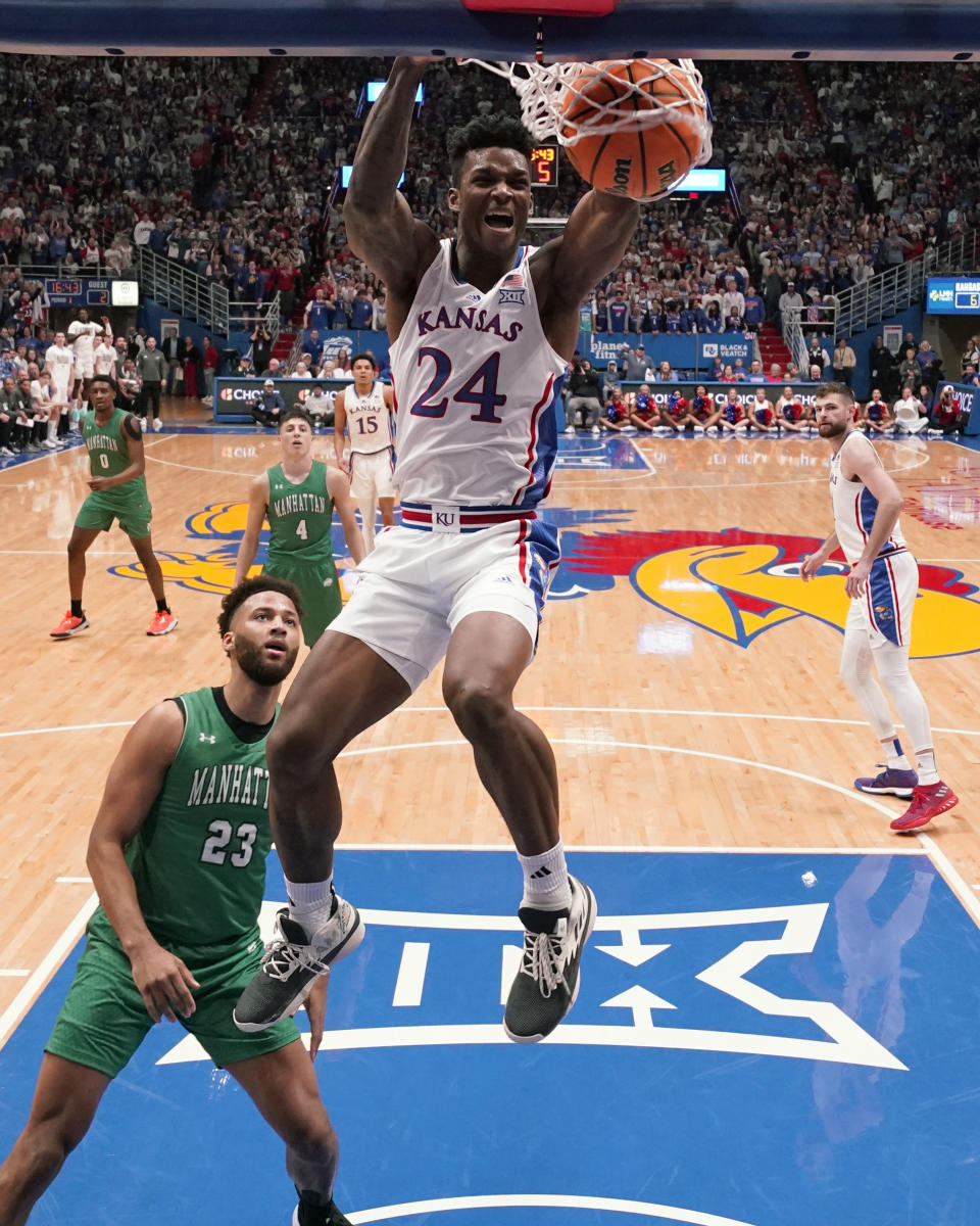 Kansas forward K.J. Adams Jr. (24) gets past Manhattan forward Daniel Rouzan (23) to dunk the ball during the first half of an NCAA college basketball game Friday, Nov. 10, 2023, in Lawrence, Kan. (AP Photo/Charlie Riedel)