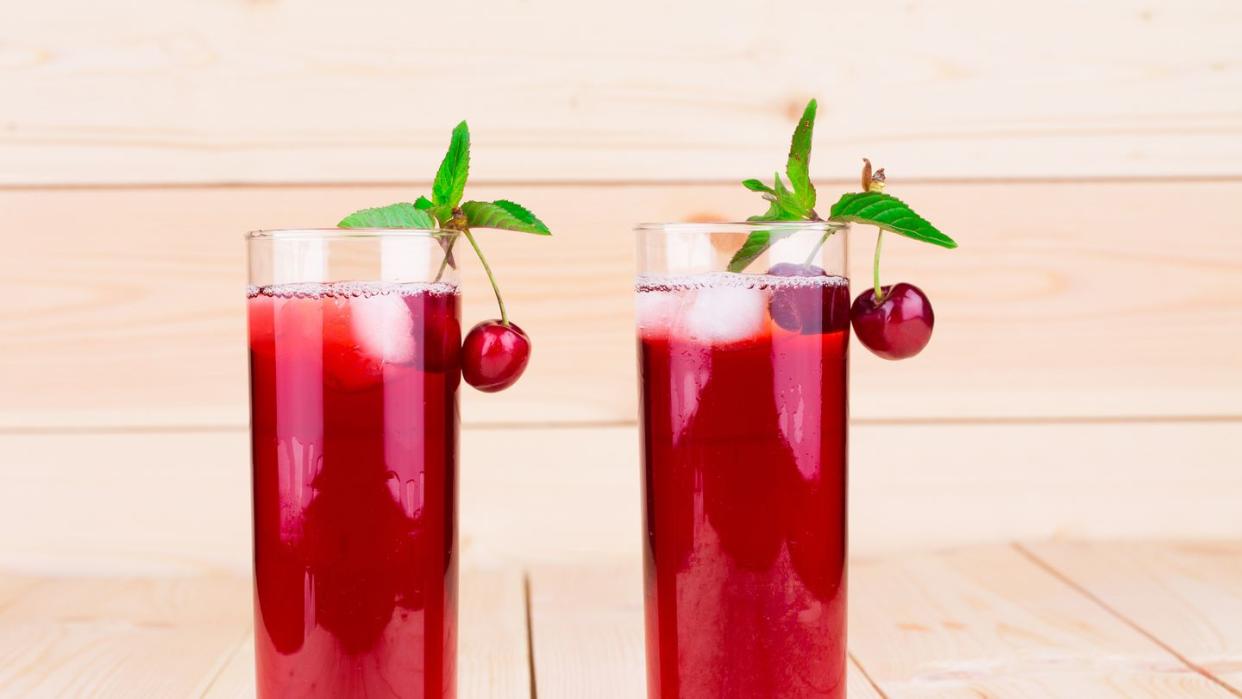 two tall glasses of tart cherry juice garnished with tart cherries