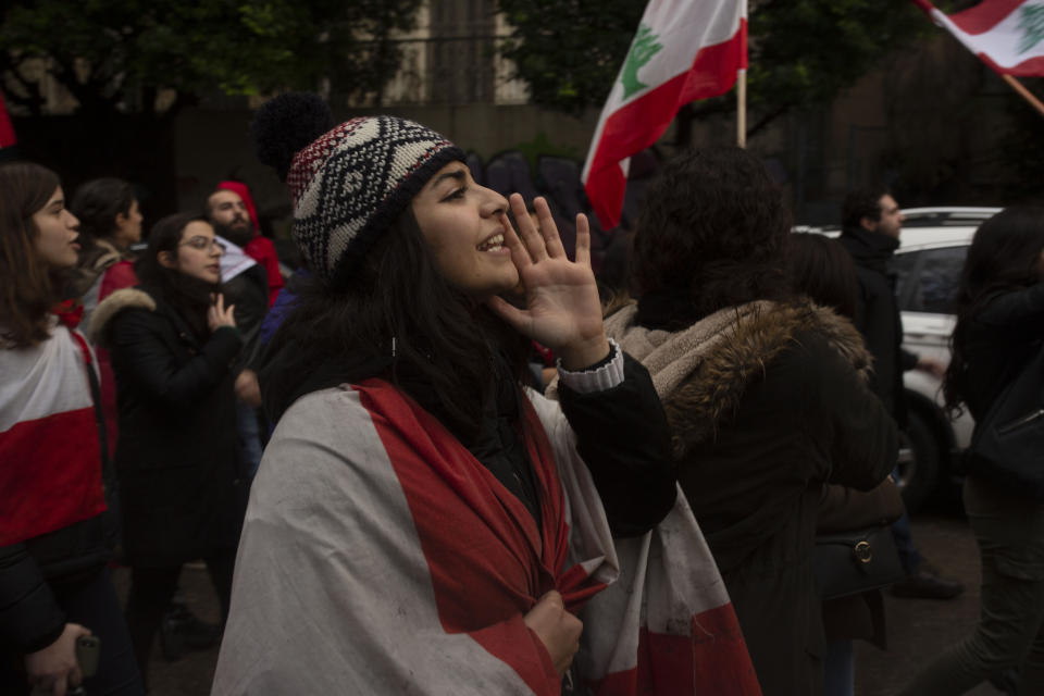 A Lebanese expatriate woman wears the national flag as she chants anti-government slogans at a protest march from the foreign ministry to the Parliament Thursday, Dec. 26, 2019 in Beirut, Lebanon. (AP Photo/Maya Alleruzzo)