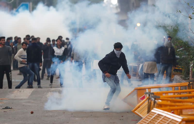 FILE PHOTO: Protesters run for cover amid tear gas fired by police during a protest against the Citizenship Amendment Bill in New Delhi